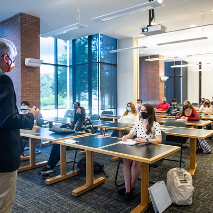 professor standing in front of classroom with students sitting socially distanced.