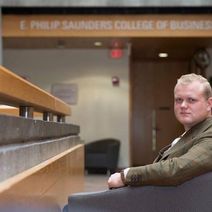 Portrait of Chance Wright sitting in the lobby of Saunders College of Business.