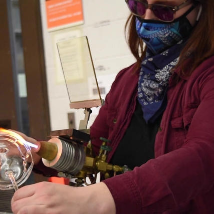 artist rotating a glass ball throw a flame.