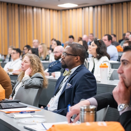 lecure hall with people sitting at long tables.