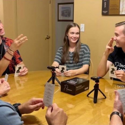 people sitting around a table playing a card game.