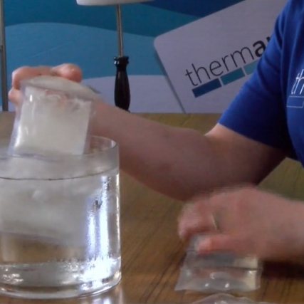 person dipping cooling packs into a container of water.