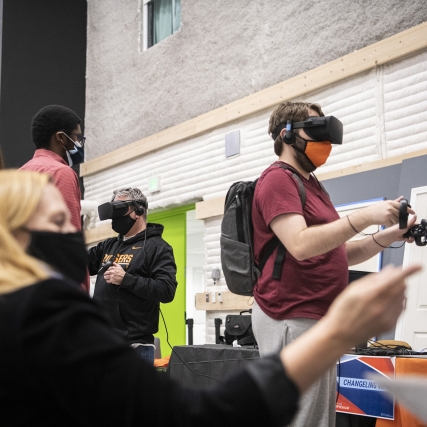 A group of people wearing VR headset demo various projects. 