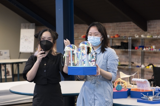 Two students hold up their game design with seascape elements