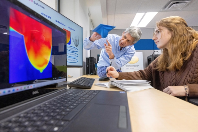 two people discusses infrared breast images in a lab.