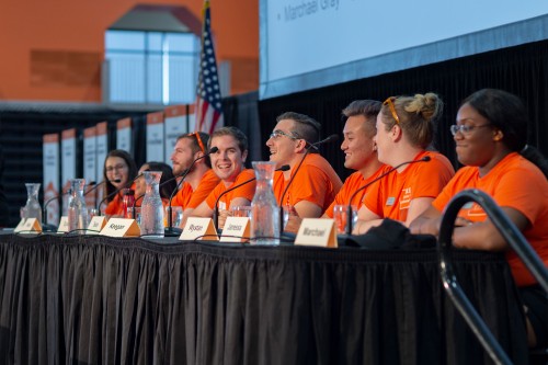 a panel of people in orange shirts