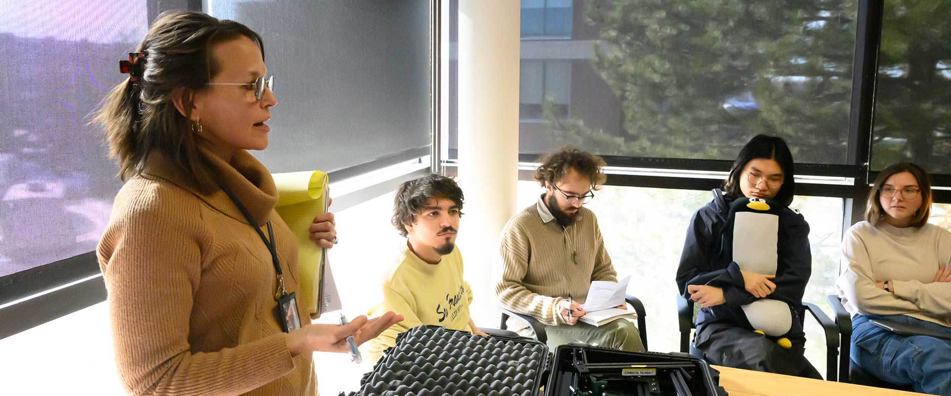 Professor giving a lecture as four seated students listen.