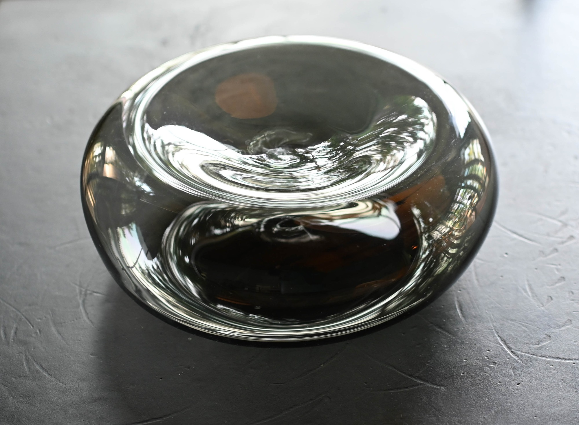 Shallow glass vessel with a rounded, pillow-like form.
