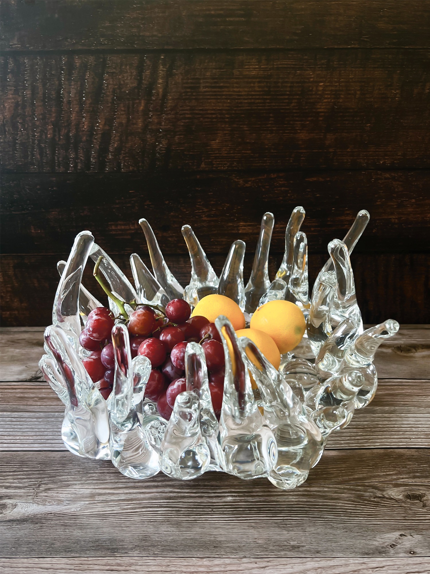 Sculptural glass base holding fruit.