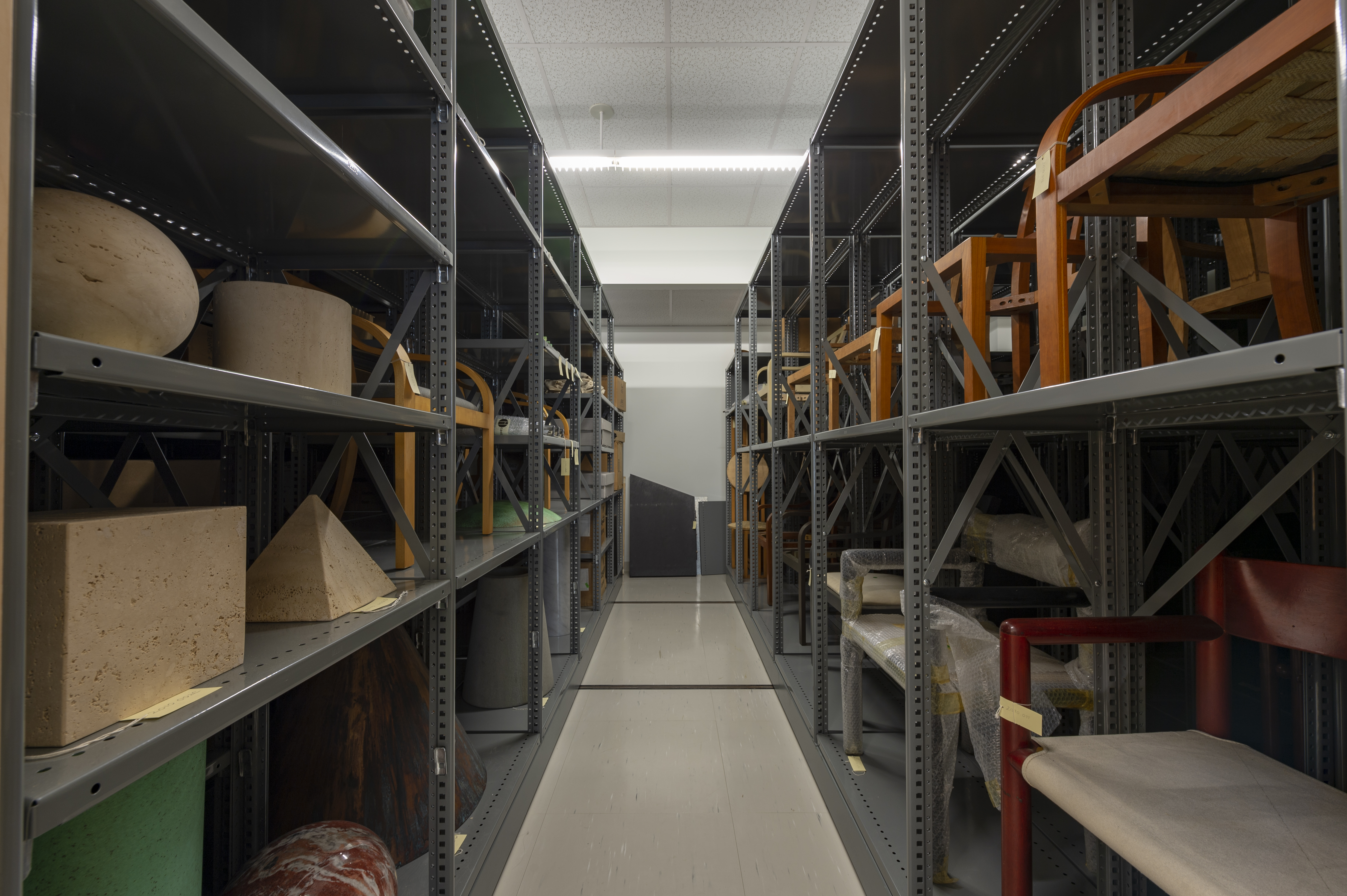 Shelving units in a storage room filled with various design objects and furniture pieces.