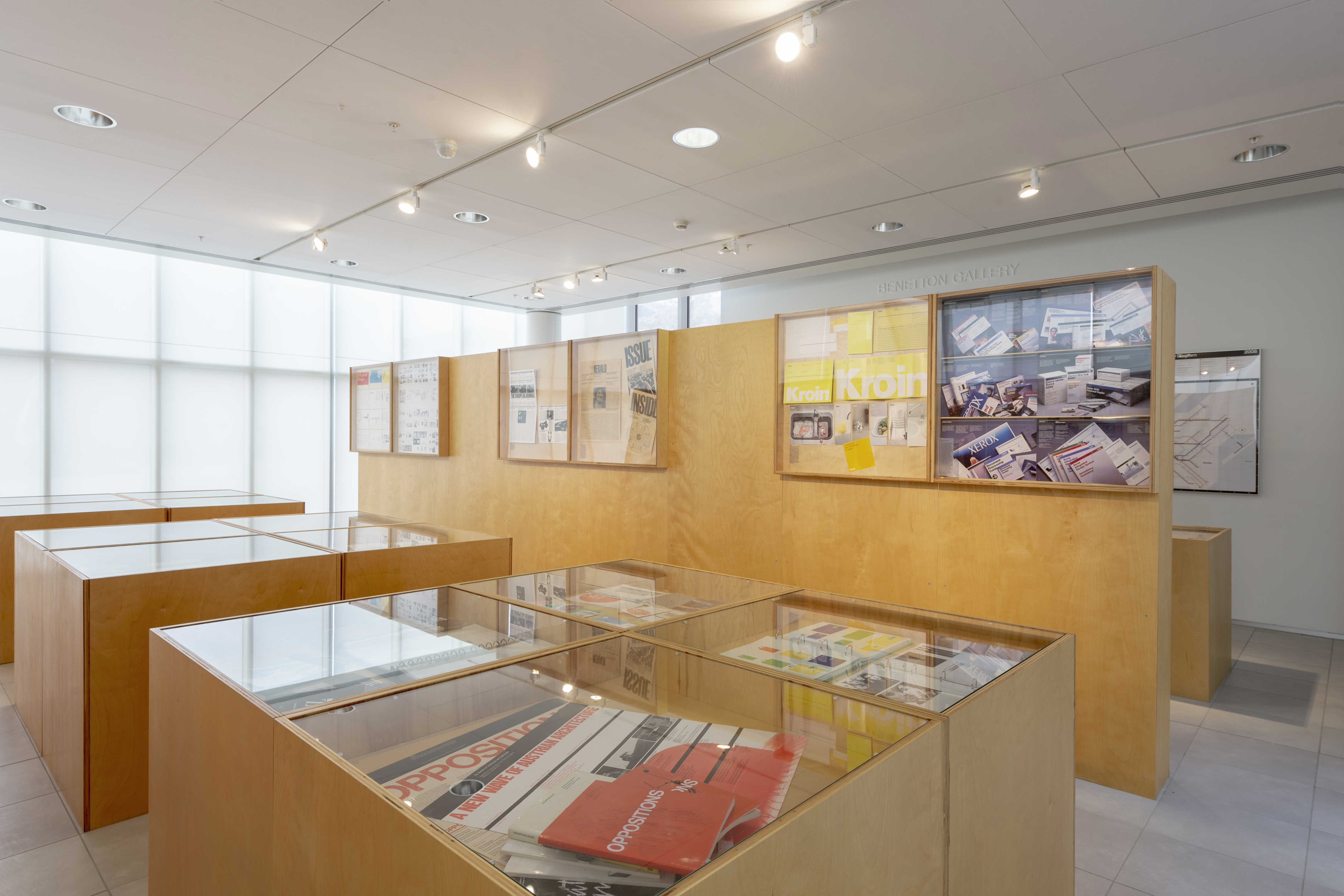 Gallery interior with wooden display cases and graphic design exhibits on the walls.