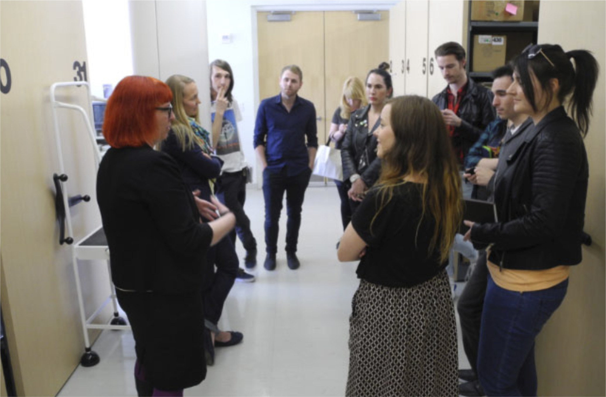 A group of people in casual attire engaged in a discussion in a hallway.