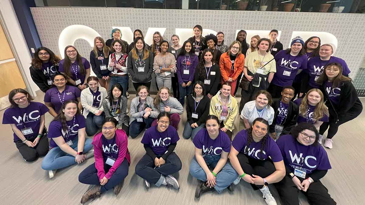 A large group of students pose together in front of a wall with the word 'CYBER' displayed.