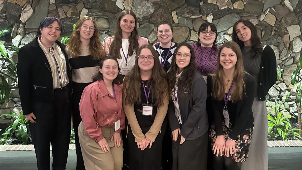 A small group of student leaders in business casual pose together and smile.
