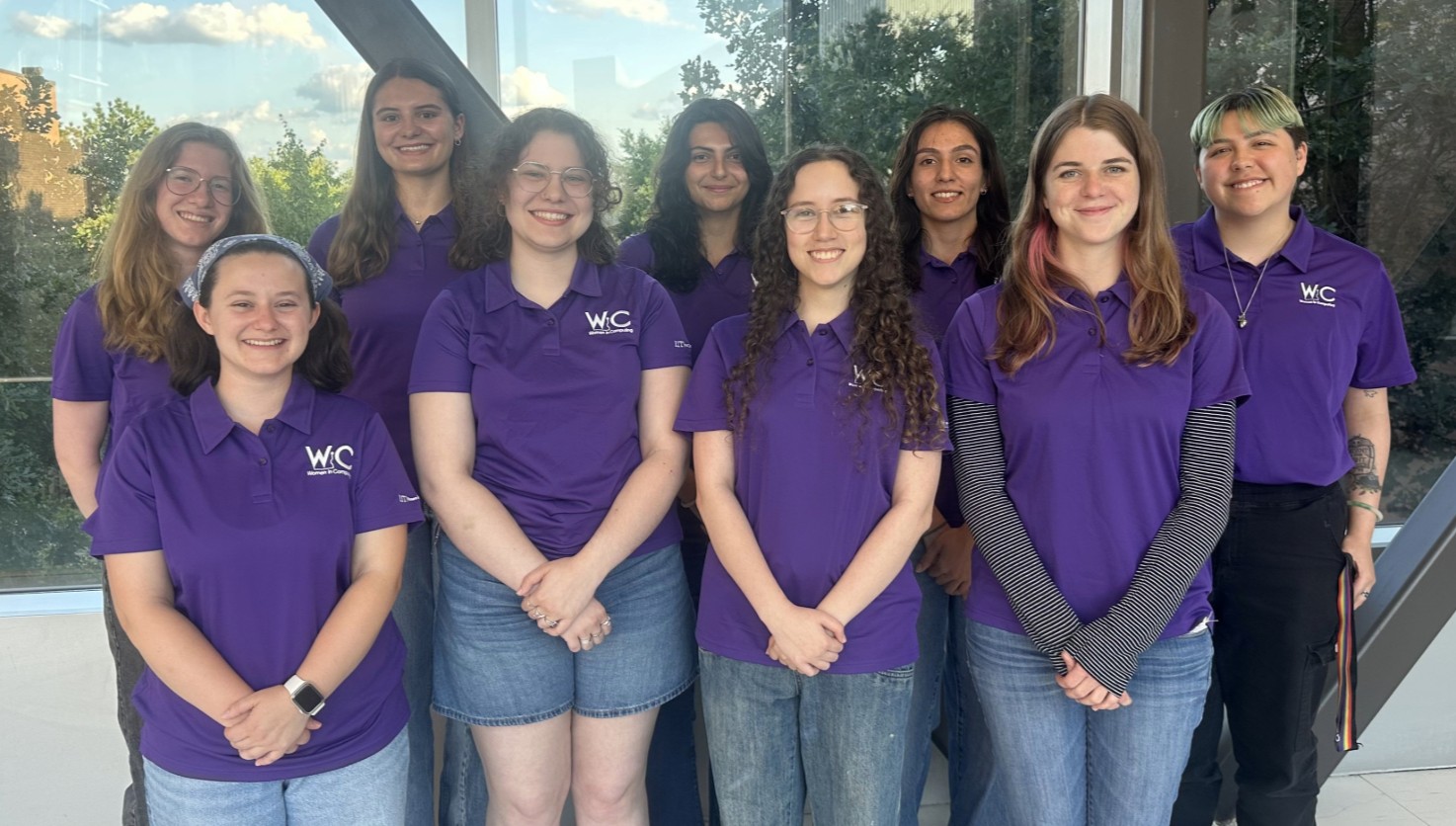 A small group of student leaders in purple polo shirts pose together and smile.