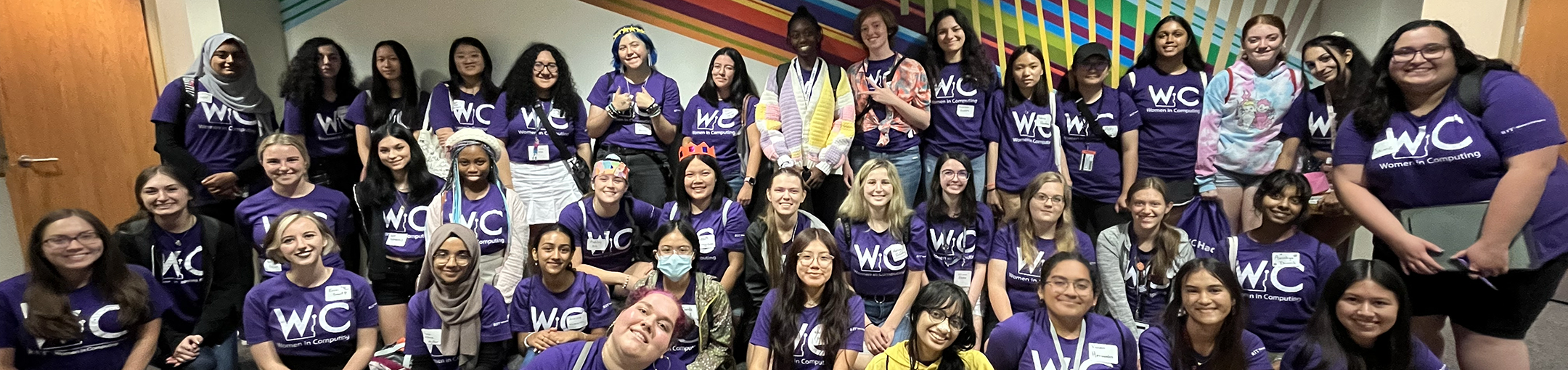 Large number of people posing for a group picture wearing WIC t-shirts