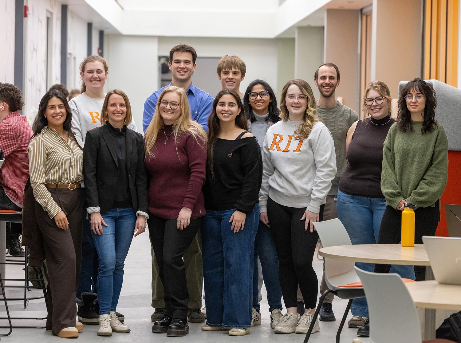 group of researchers poses for a photo in a hallway.