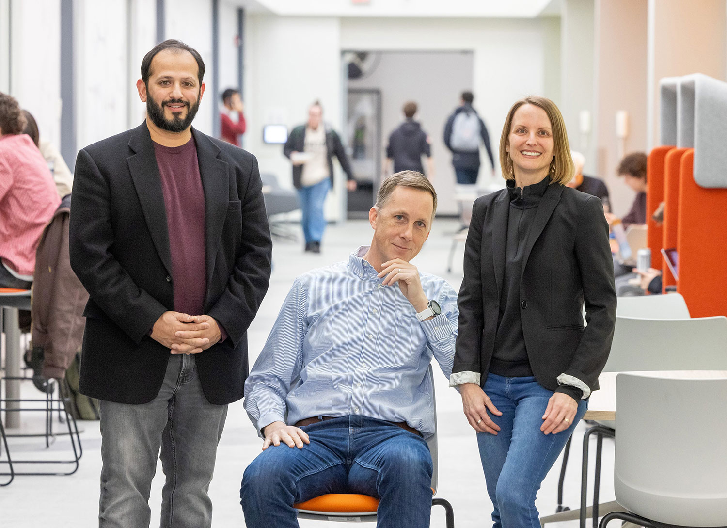 three researchers pose for a photo in a busy hallway.