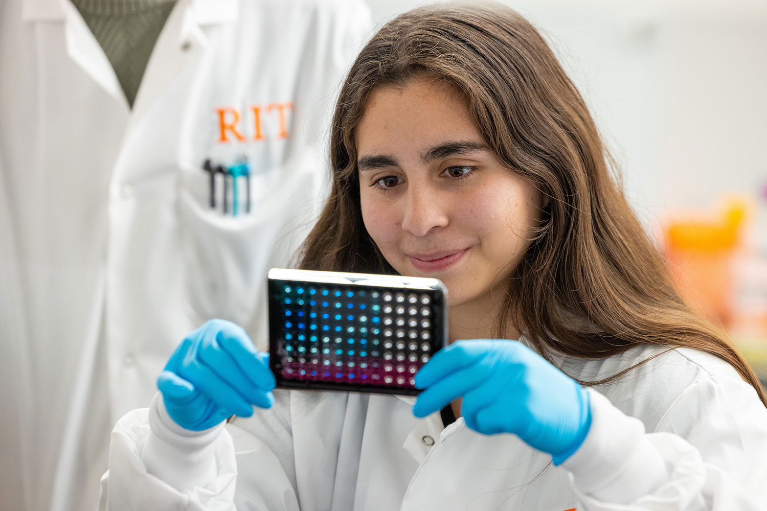 student researcher looks at a device with several colored circles.
