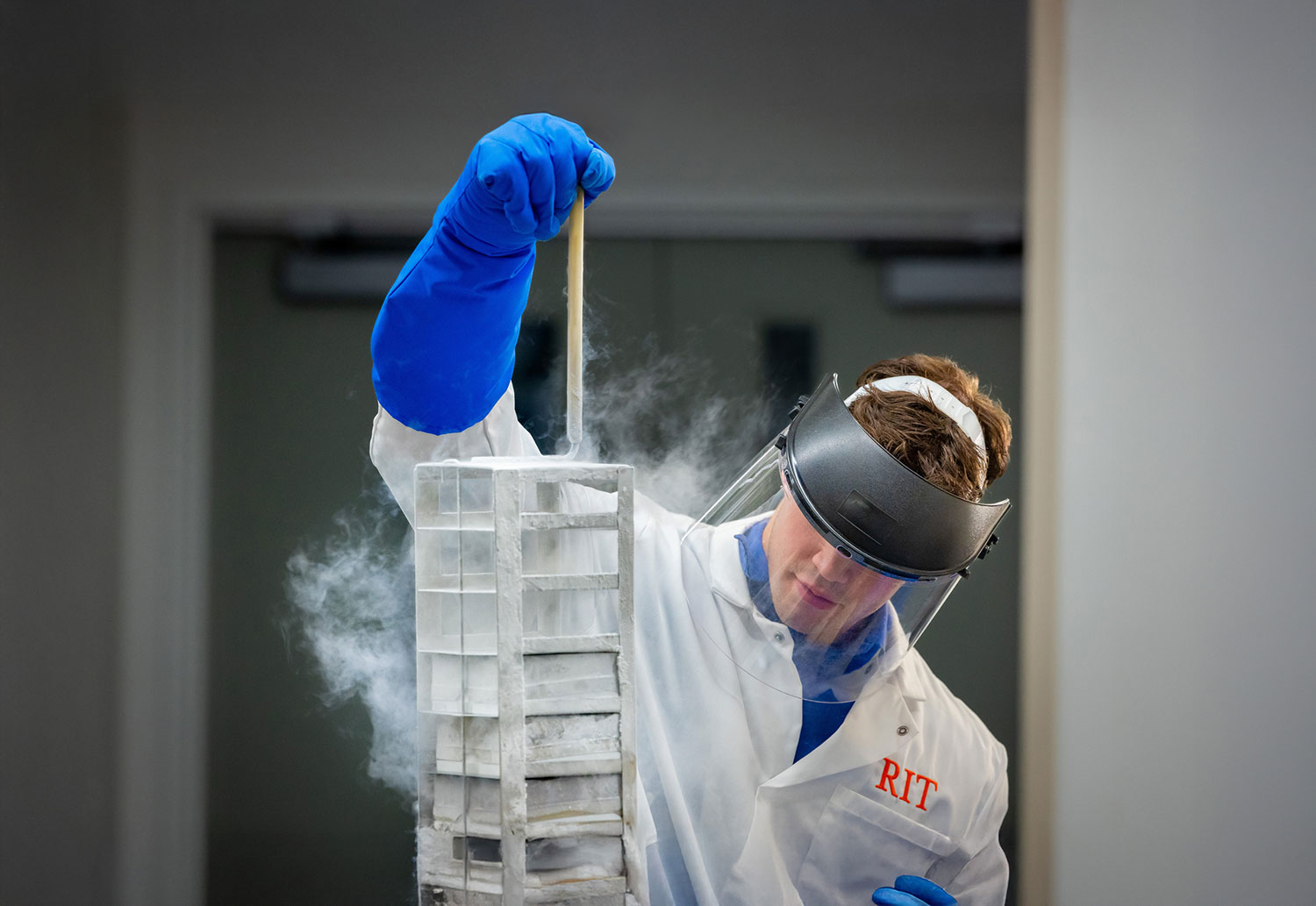 student researcher wearing protective mask and gloves pulls a vertical tray of samples from cold storage.