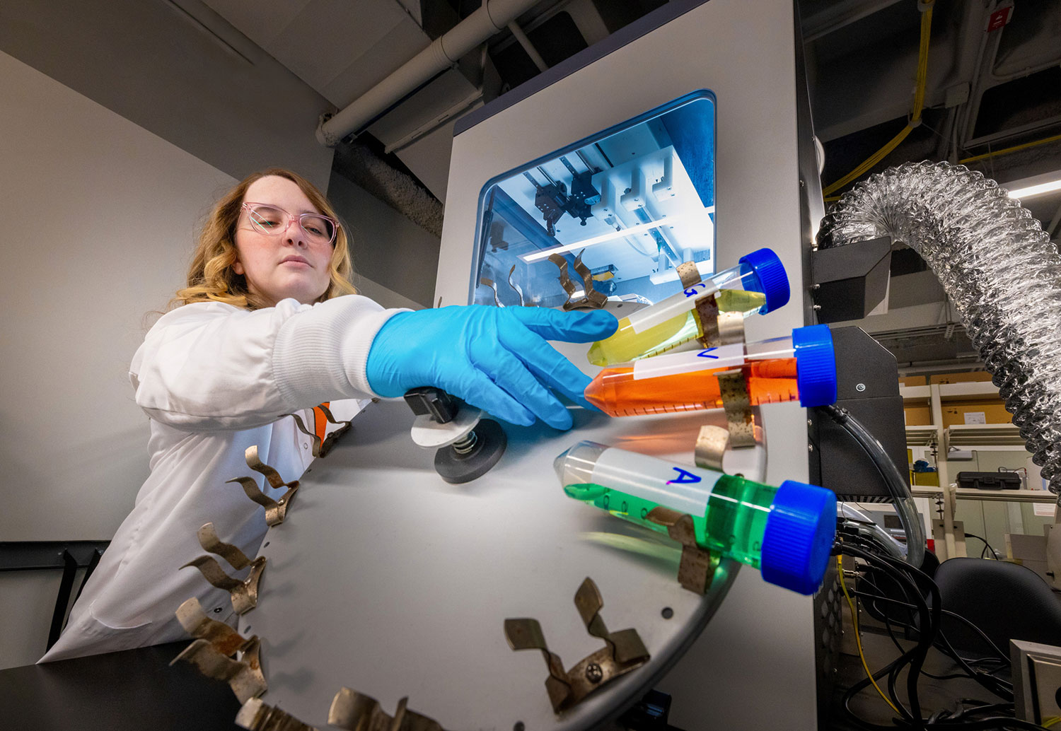 student researcher adjusts tubes on a large centrifuge machine.