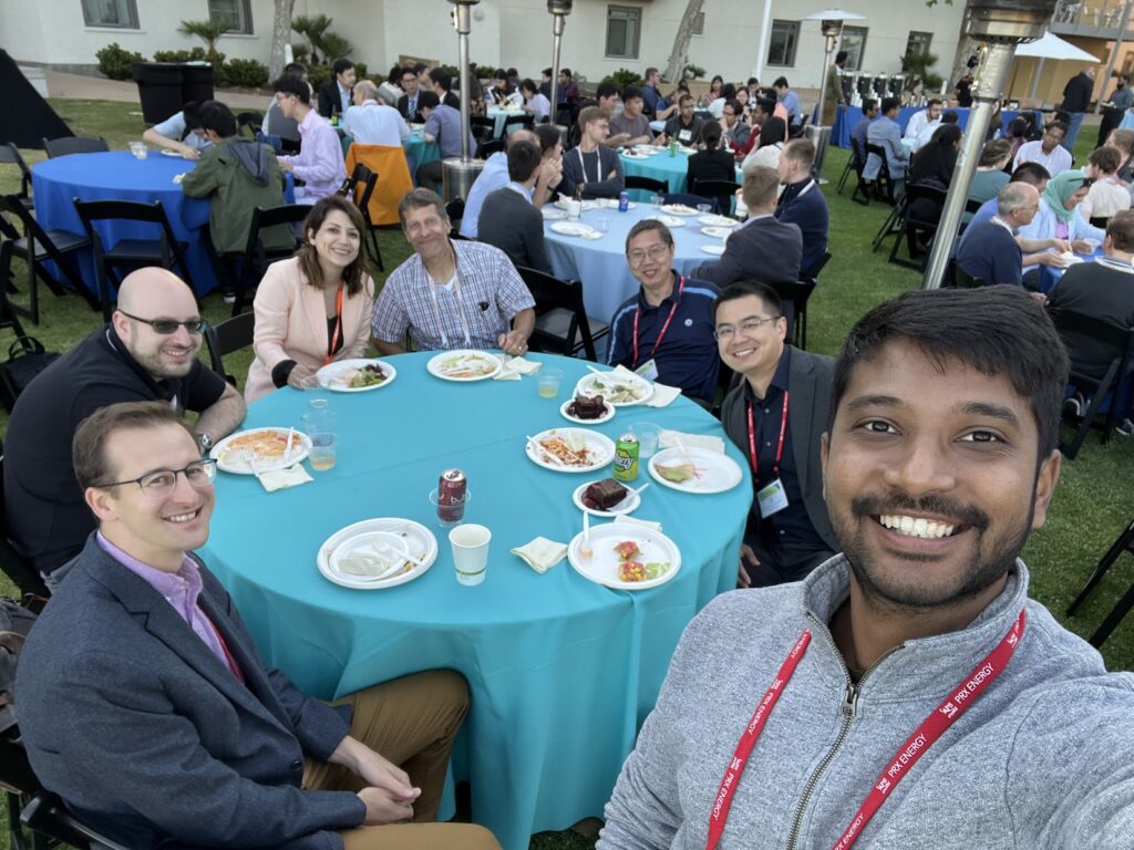 Conference attendees, including Xu Group members, seated together at an outdoor event table.