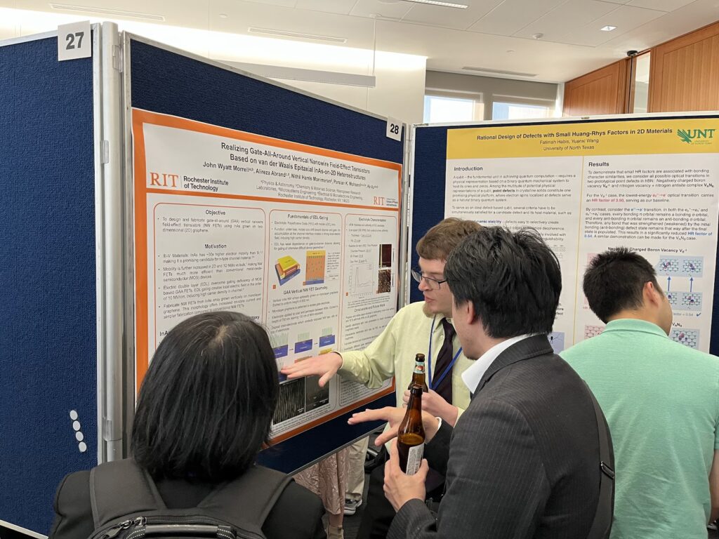 A conference attendee presents an RIT research poster about vertical nanowire field-effect transistors to several people at a poster session for the 10th Graphene and Beyond Workshop. The poster board includes diagrams, graphs, and microscopy images, with additional research posters visible nearby.