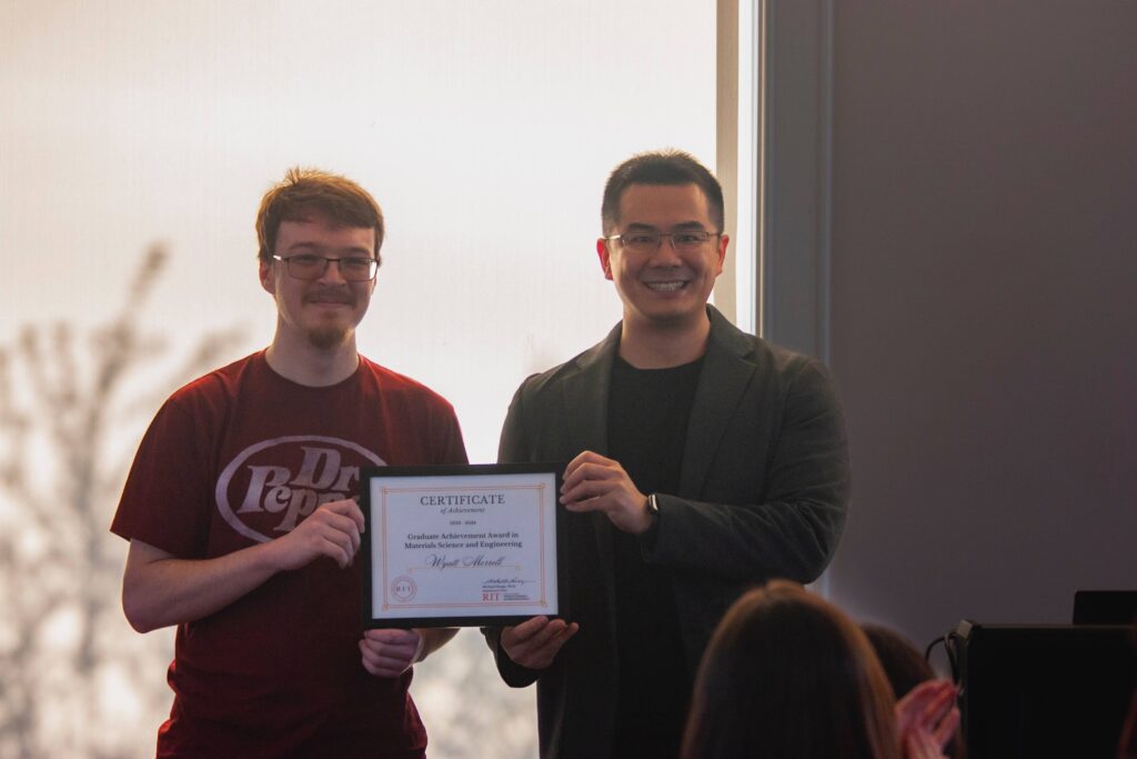 Wyatt holding an award certificate with Dr. Xu during a presentation.