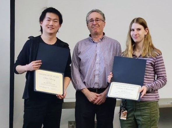 Steve and another student holding award certificates with a faculty member between them.