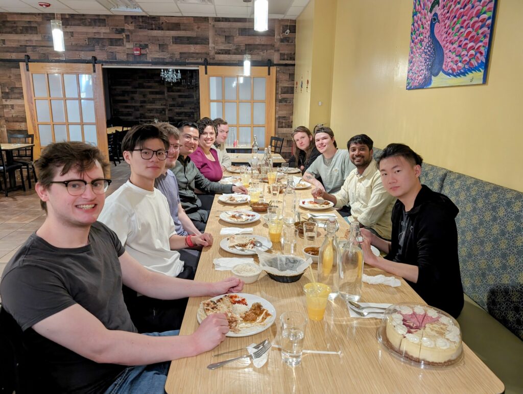 Xu Group members seated together at a restaurant table celebrating student achievements.