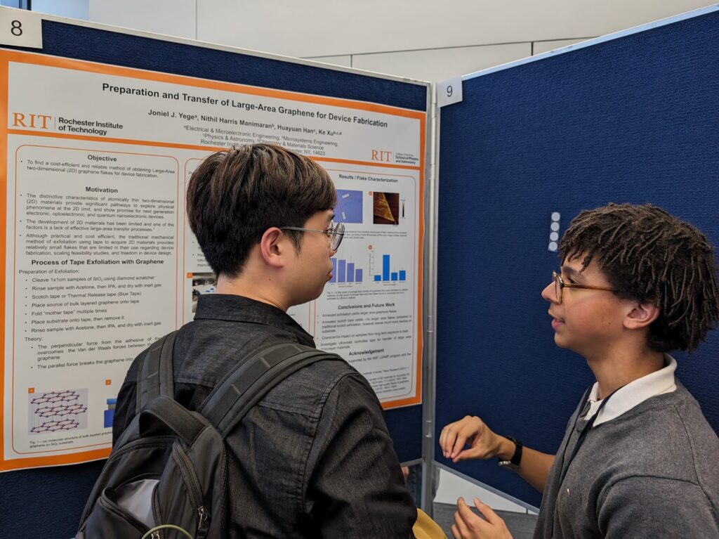 A student discussing a poster about layer-dependent properties of heterostructures with another attendee.