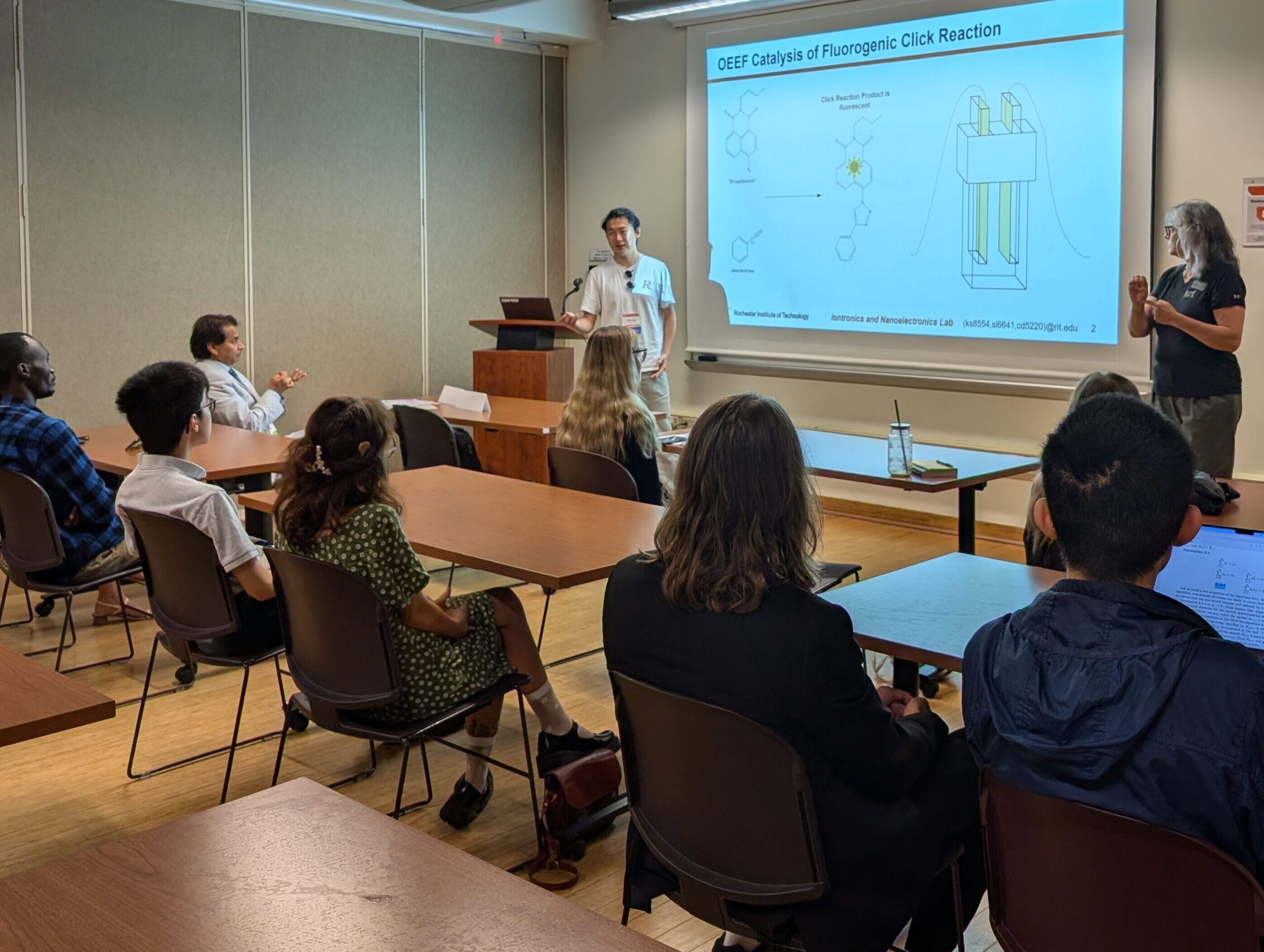A student presenting a slide on electric double layer devices to an audience in a classroom.