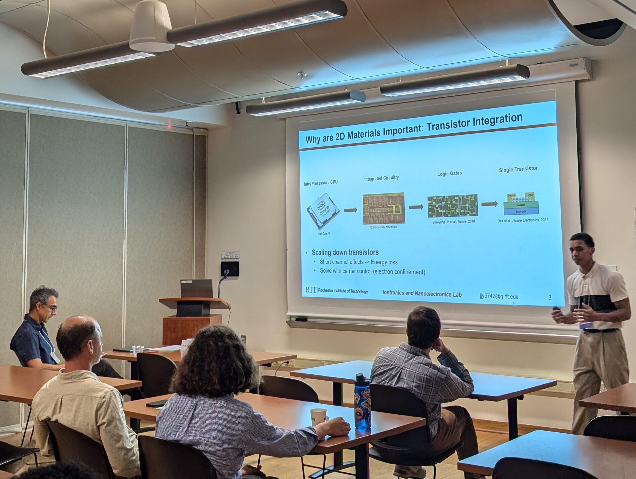 A student presenting a slide about transistor integration for 2D materials to an audience.