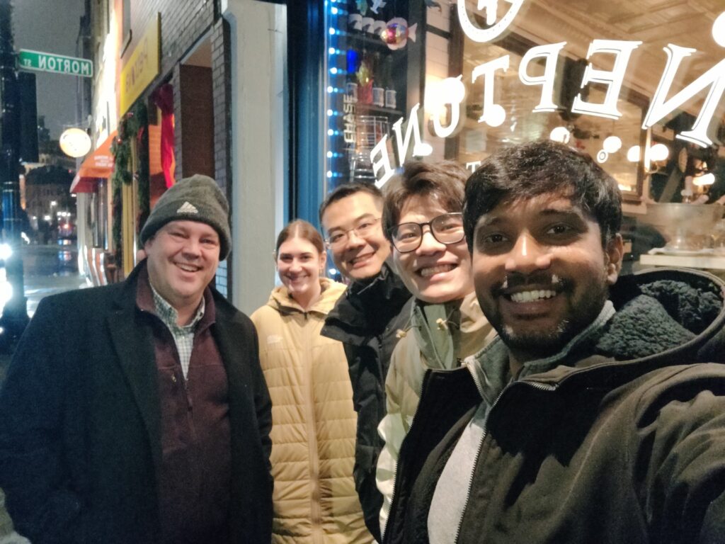 Nithil and colleagues taking a nighttime group selfie outside a seafood restaurant.