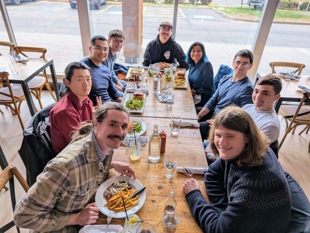 Dr. Xu, Dr. Lanata, Dr. Das, and incoming Physics PhD students seated around a restaurant table.