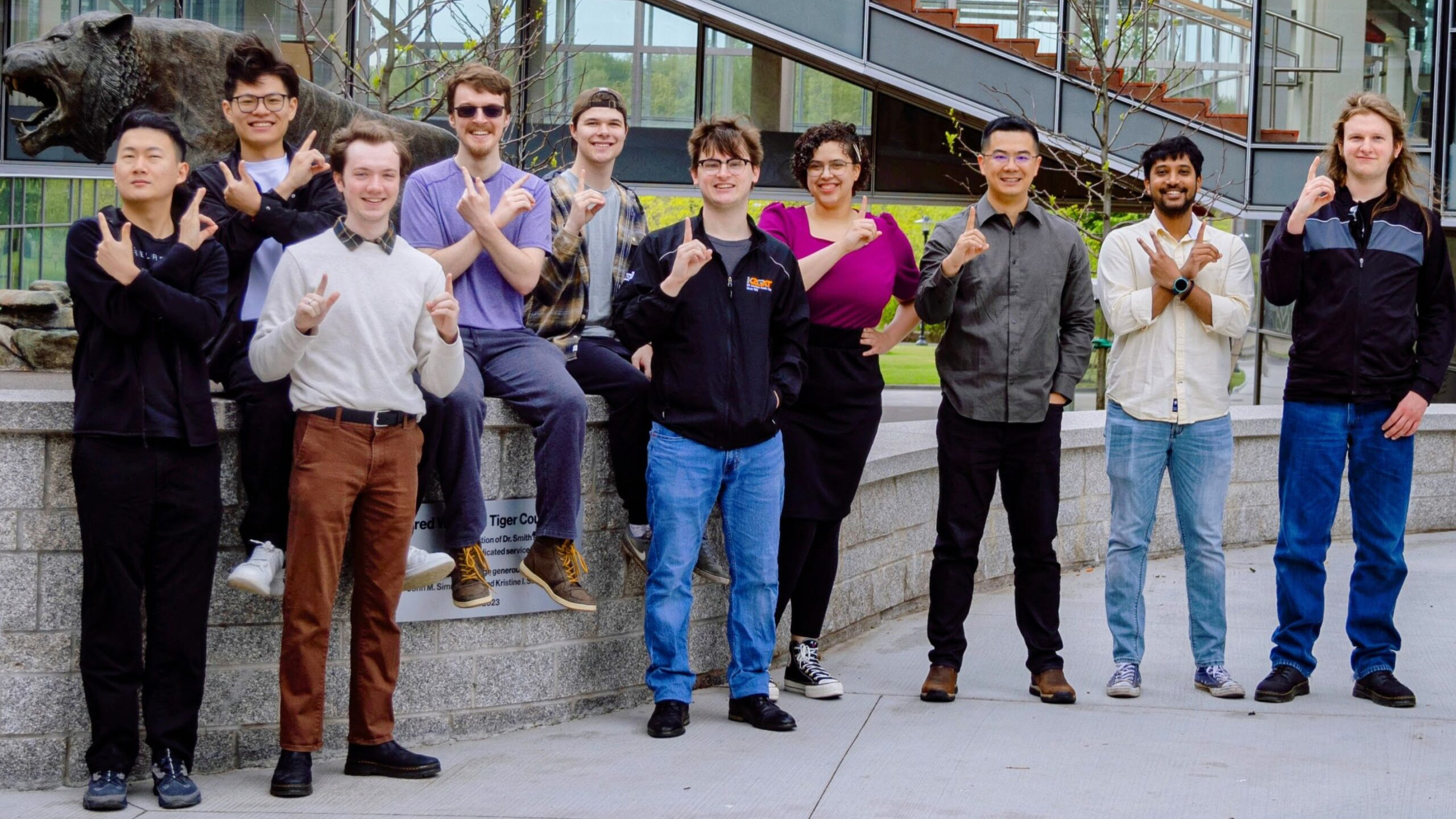 Xu Group members posing together outside on campus near the tiger statue.