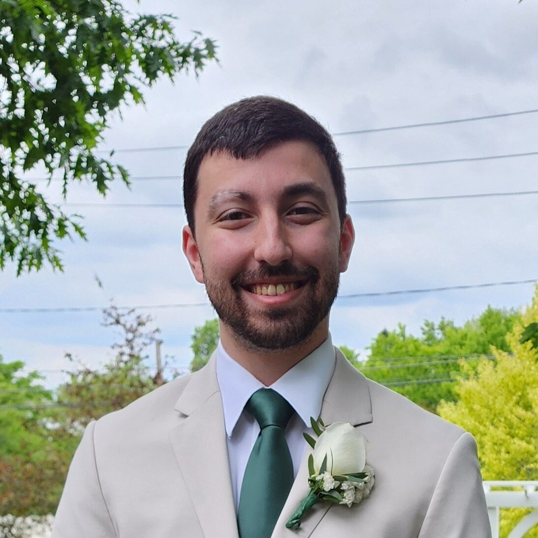 Jon Dixon smiling outdoors in formal attire with a boutonniere.