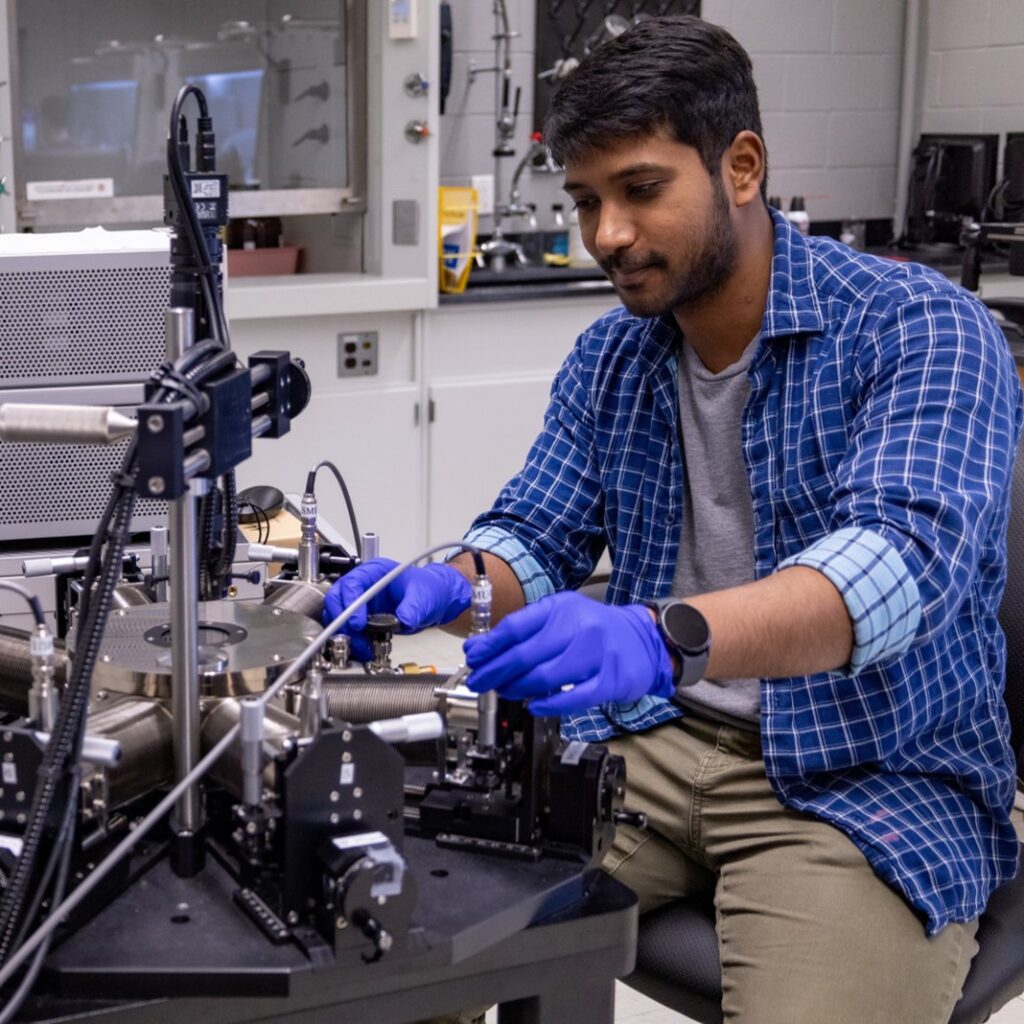Nithil Harris Manimaran working with lab equipment at a probe station while wearing gloves.