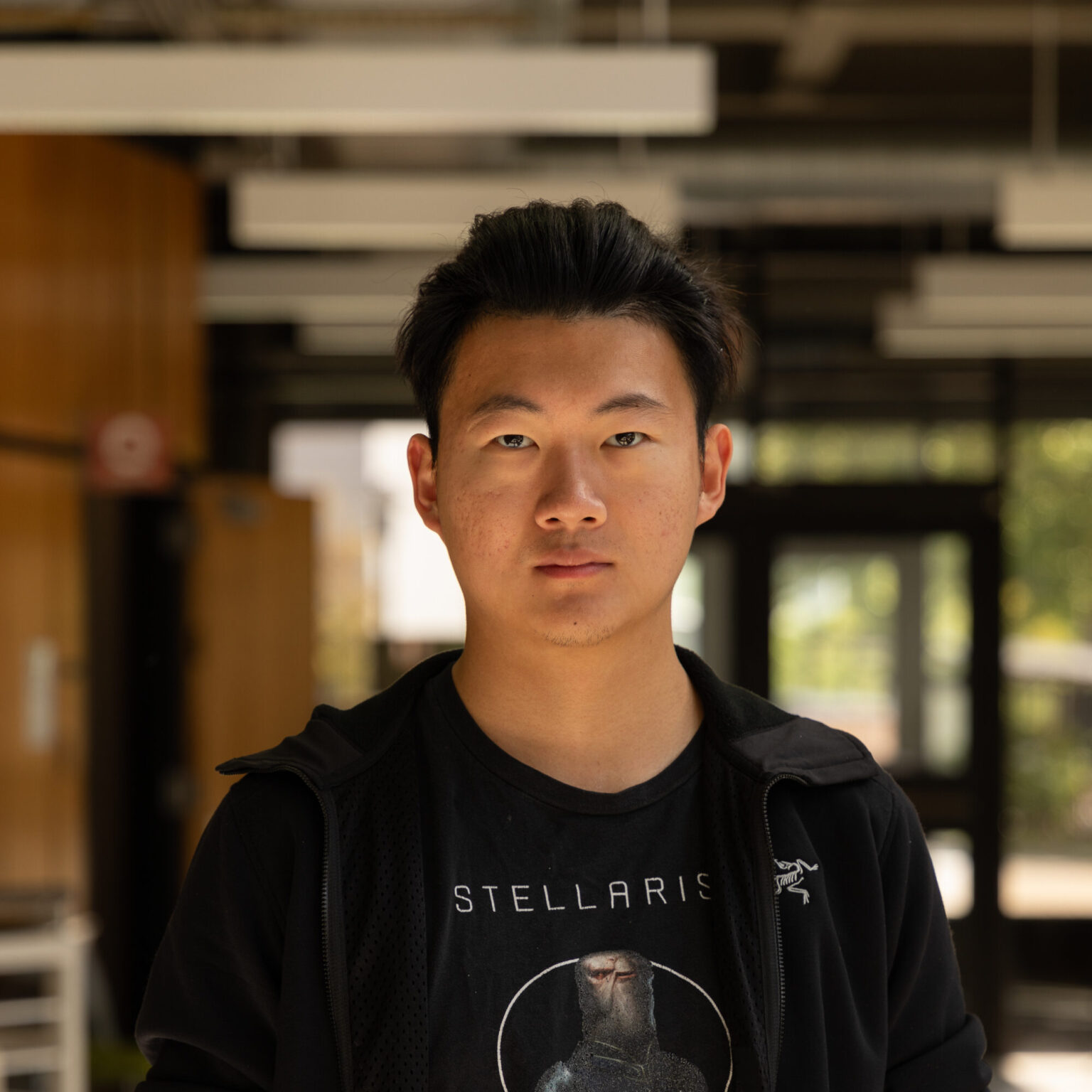Steve Zehua Liang standing indoors in a black jacket and Stellaris T-shirt.
